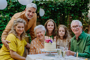 Eine Mehrgenerationen-Familie auf einem Sommergartenfest im Freien, die ihren Geburtstag feiert - HPIF09579