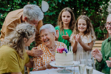 Eine Mehrgenerationen-Familie auf einem Sommergartenfest im Freien, die ihren Geburtstag feiert - HPIF09580