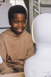 Curious boy looking at AI social robot in innovation lab - MASF36749