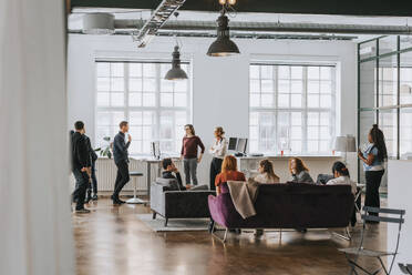 Male and female business people discussing with each other at modern work place - MASF36783