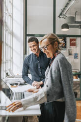 Glückliche männliche und weibliche Geschäftsleute am Schreibtisch in einem modernen Büro - MASF36830