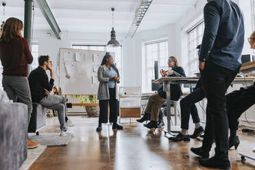 Multiracial colleagues listening to businesswoman explaining strategy during meeting in office - MASF36837