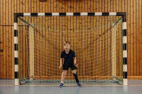 Focused male goalie with disability standing in front of net at sports court - MASF36864