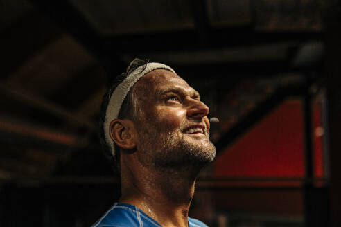 Smiling male athlete wearing headband while contemplating at sports court - MASF36879