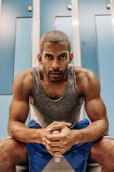 Determined male athlete with muscular build sitting in locker room - MASF36907