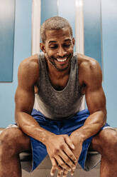 Happy male athlete with eyes closed sitting in locker room - MASF36908