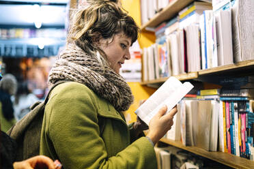 Frau mit Kopftuch liest in einer Bibliothek ein Buch - AMWF01364