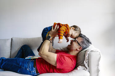 Glücklicher Vater spielt mit seinem Sohn auf dem Sofa zu Hause - JJF00958