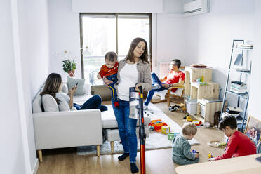Mutter reinigt Haus mit Familie im Wohnzimmer zu Hause - JJF00964