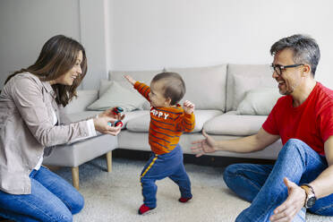 Vater und Mutter spielen mit ihrem Sohn im heimischen Wohnzimmer - JJF00965