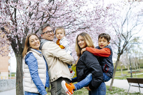 Glückliche Familie vor einem Kirschblütenbaum stehend - JJF00966
