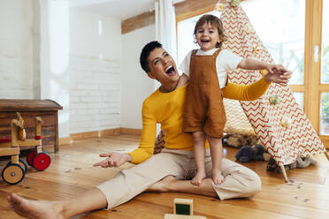 Happy mother playing with son in living room at home - EBSF03275