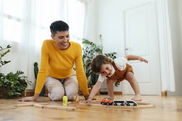 Happy son playing with toy train by mother at home - EBSF03280