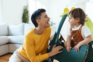 Glückliche Frau mit Sohn in Spielzeugauto zu Hause - EBSF03285