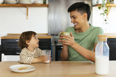 Smiling woman having breakfast with son at home - EBSF03290