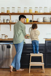 Frau wäscht mit ihrem Sohn in der Küche zu Hause ab - EBSF03292