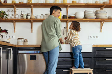 Glückliche Frau und Sohn beim Abwaschen in der Küche zu Hause - EBSF03293