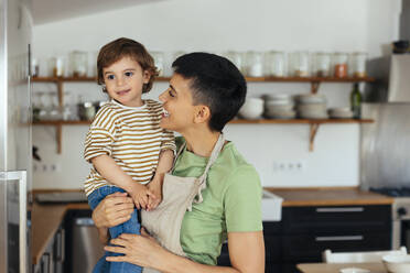 Happy woman carrying son in kitchen at home - EBSF03298