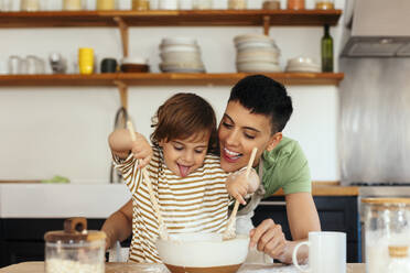 Son mixing flour by mother in kitchen at home - EBSF03303