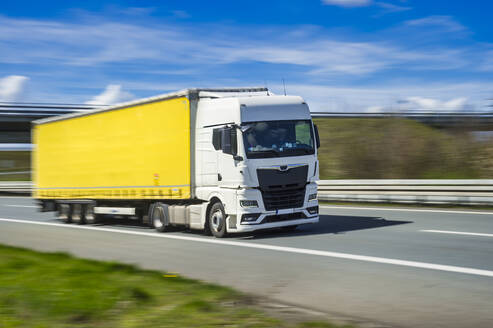 Germany, North Rhine Westphalia, Yellow truck driving along A 46 - FRF01017