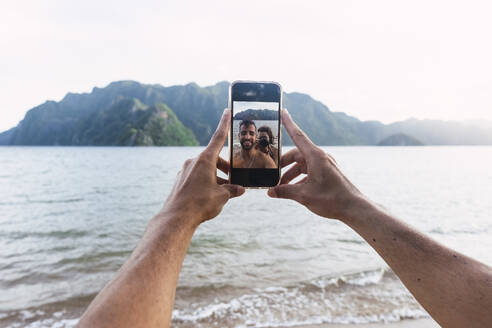 Couple taking selfie through smart phone at vacation - PNAF05279