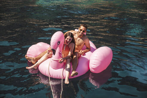 Paar, das seinen Urlaub auf einer Flamingo-Luftmatratze genießt, im Urlaub - PCLF00526