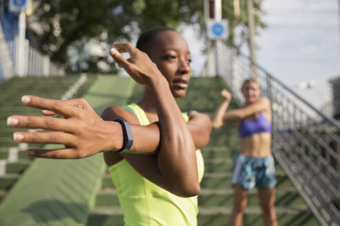 Frau mit Fitness-Tracker dehnt sich mit Freundin - IKF00444