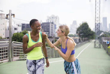 Happy friends in sports clothing enjoying on footpath - IKF00465