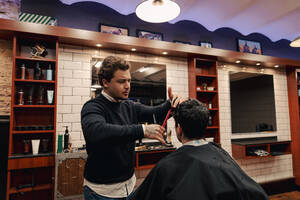 Friseur schneidet Haare eines Kunden im Laden sitzend - ACPF01552