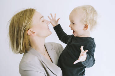 Playful son with mother against white background - NDEF00607