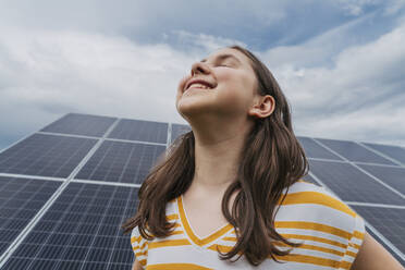 Smiling girl with eyes closed in front of solar panels - OSF01546