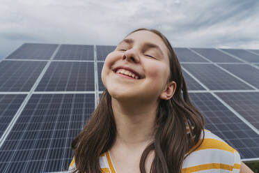 Happy girl with eyes closed in front of solar panels - OSF01547