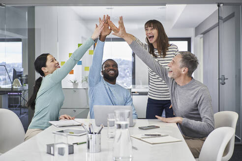 Happy business colleagues giving high-five in meeting room - RORF03541