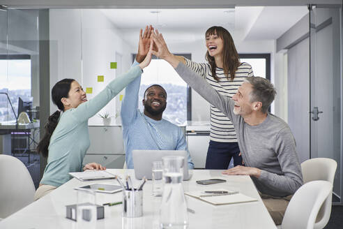 Happy colleagues giving high-five in office meeting - RORF03542