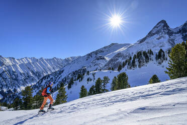 Österreich, Tirol, Die Sonne scheint über einer Skifahrerin am Torhelm - ANSF00266