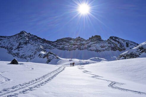 Österreich, Tirol, Sonnenschein über Skifahrern, die im Hollensteinkar durch den Schnee fahren - ANSF00273