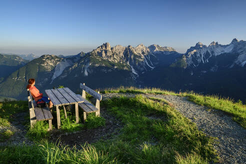 Italien, Provinz Belluno, Wanderin sitzt am Gipfeltisch auf dem Monte Punta - ANSF00317