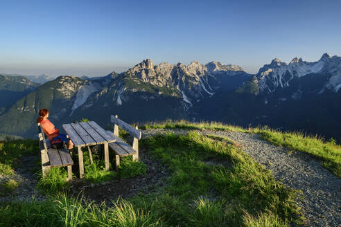Italy, Province of Belluno, Female hiker sitting at mountaintop table at Monte Punta - ANSF00317