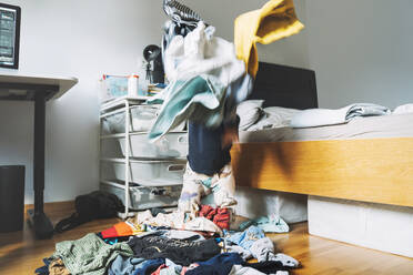 Kleinkind Junge spielt mit unordentlichen Kleidung im Schlafzimmer zu Hause - NDEF00613