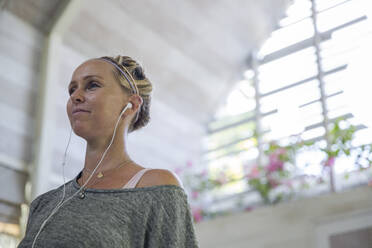 Frau mit In-Ear-Kopfhörern zu Hause - IKF00529