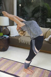 Frau macht Yoga auf einer Übungsmatte zu Hause - IKF00542