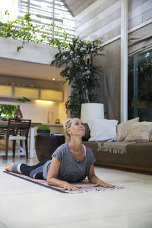 Frau übt Sphinx-Pose auf Übungsmatte zu Hause - IKF00546