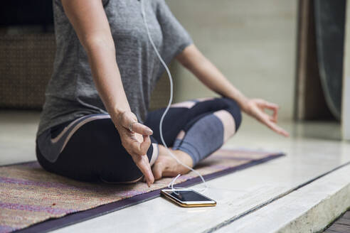 Frau übt Lotus Position sitzen im Schneidersitz von Smartphone zu Hause - IKF00575