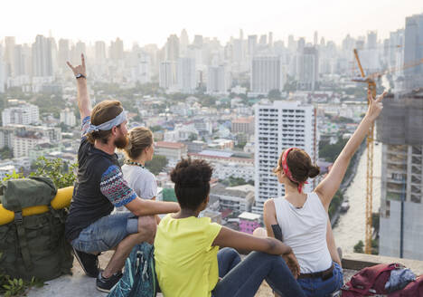 Friends looking at city view from rooftop - IKF00578