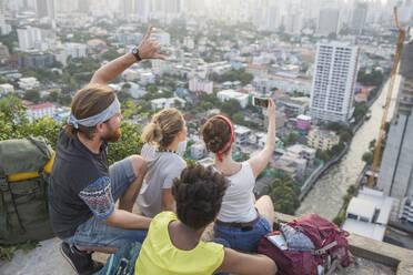 Friends taking selfie with smart phone at rooftop in city - IKF00581