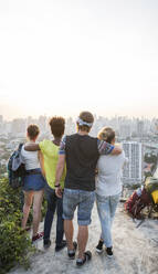 Friends enjoying city view from rooftop at sunset - IKF00585