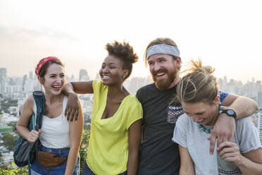 Freunde lachen zusammen mit der Stadt im Hintergrund bei Sonnenuntergang - IKF00588