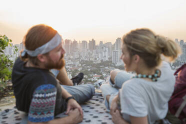 Couple spending leisure time on rooftop at sunset - IKF00592
