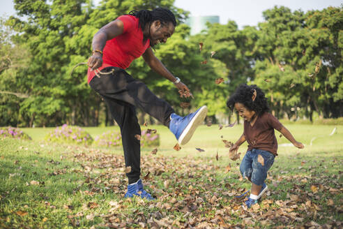 Vater und Sohn spielen mit getrockneten Blättern im Park - IKF00616