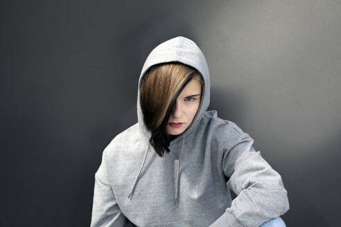 Teenage girl wearing hooded shirt against gray background - PSTF01052